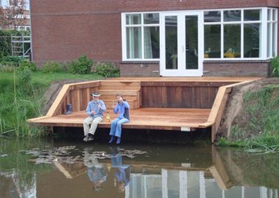Houtbouw vlonder aan het water met mensen die wat drinken