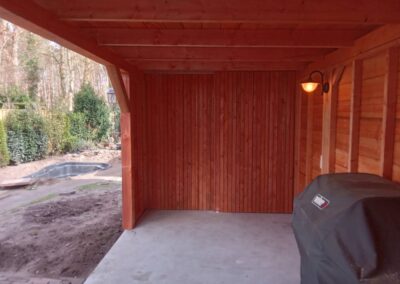 Houten overkapping met een weber barbecue op de voorgrond