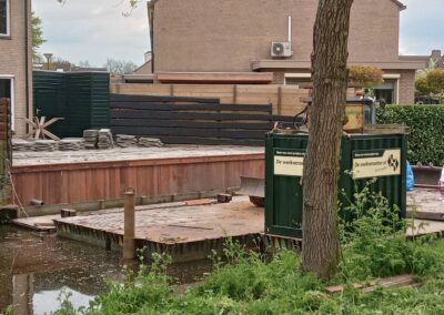Overzicht van een damwand die wordt geplaatst. In de voorgrond een container van de werkverzetter